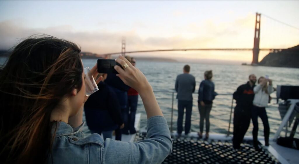 A tourist takes a photo of the Golden Gate Bridge with her cell phone while sailing on the bay.